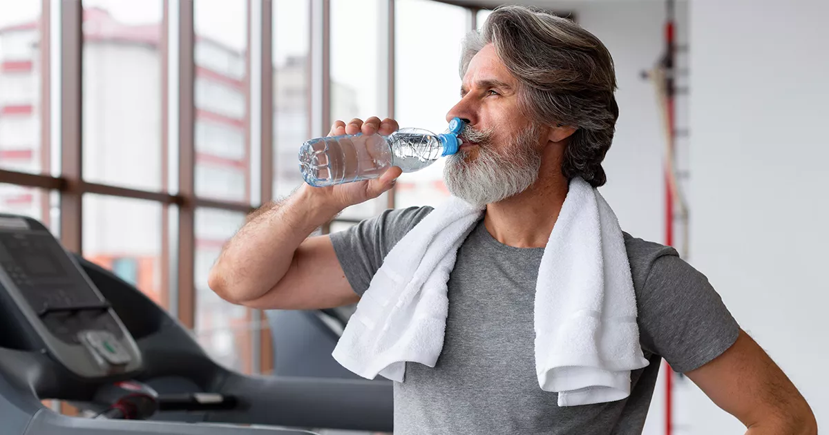 Homem idoso bebendo água em uma academia. Matéria sobre longevidade para o blog do Bradesco Saúde.